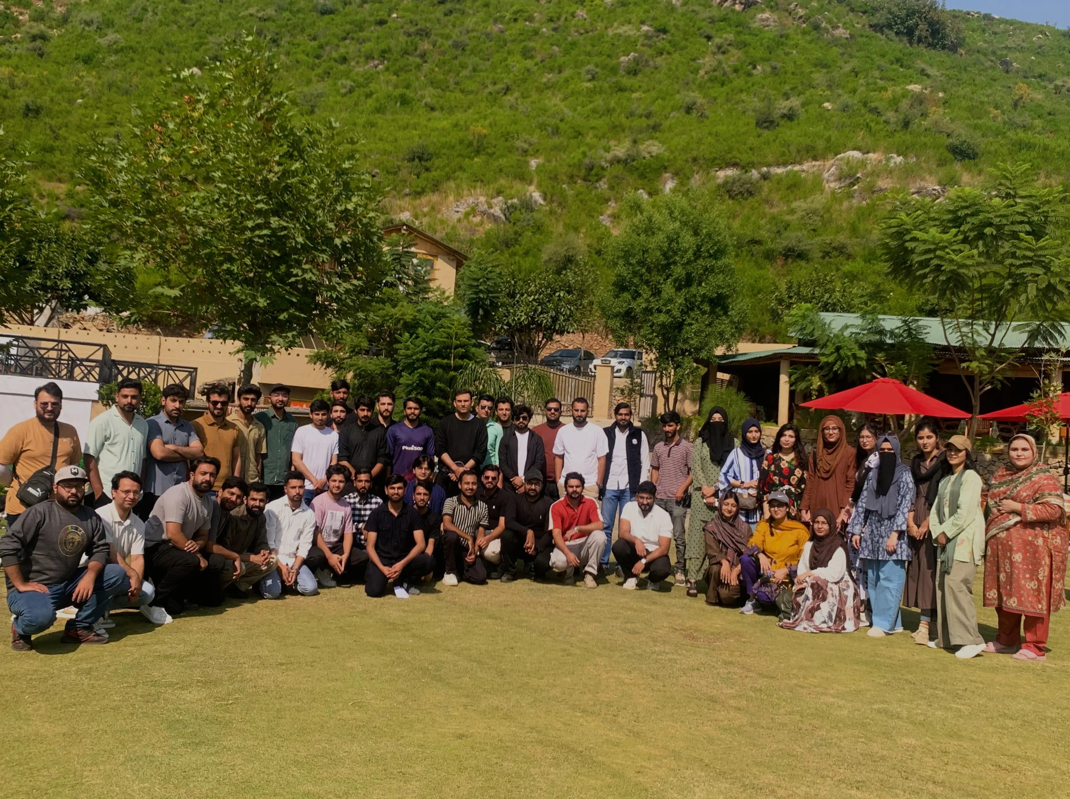 The team gathered on a lakeside lawn with hills behind