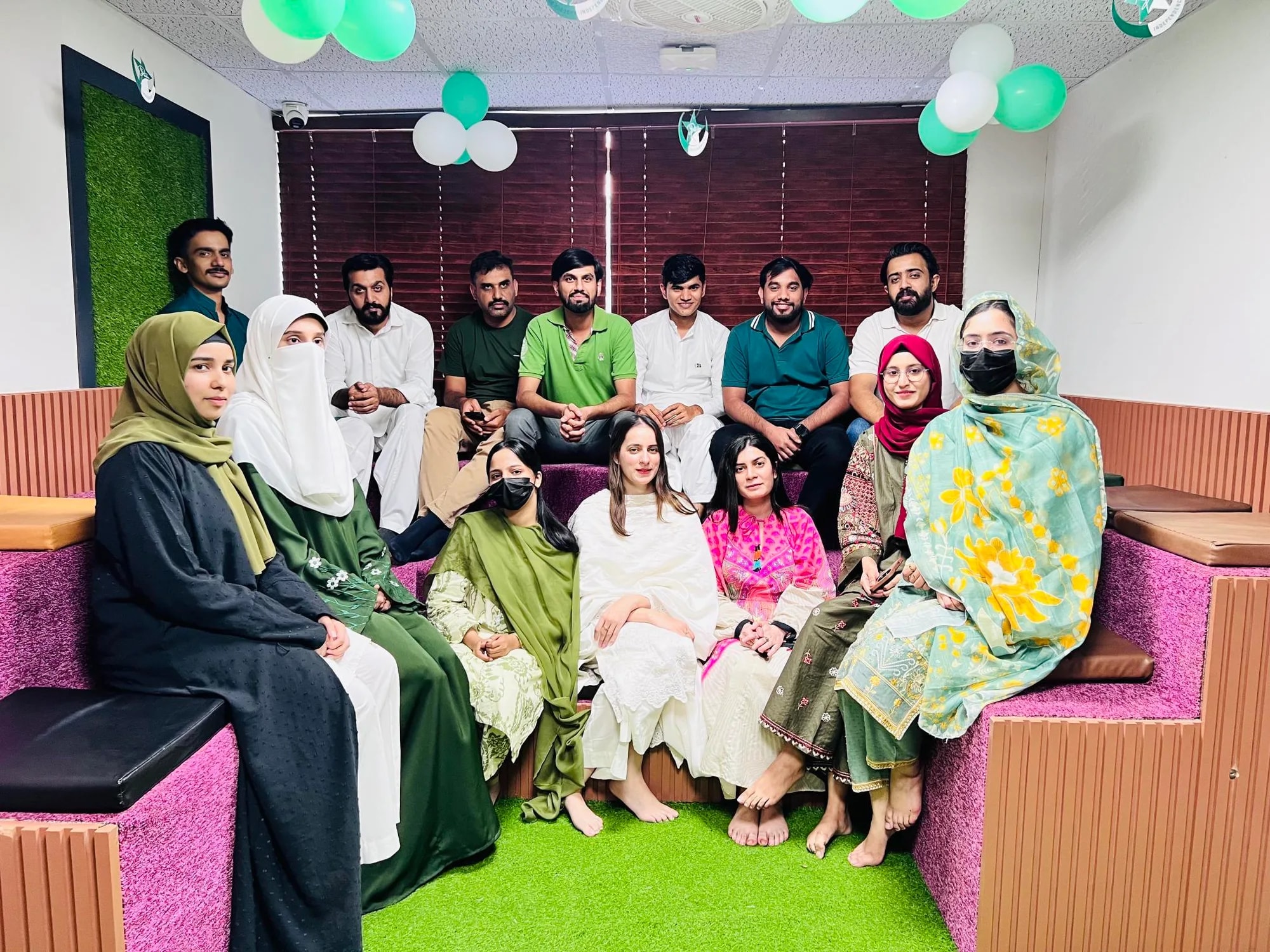 The team dressed in green and white, gathered under green and white balloons at the office