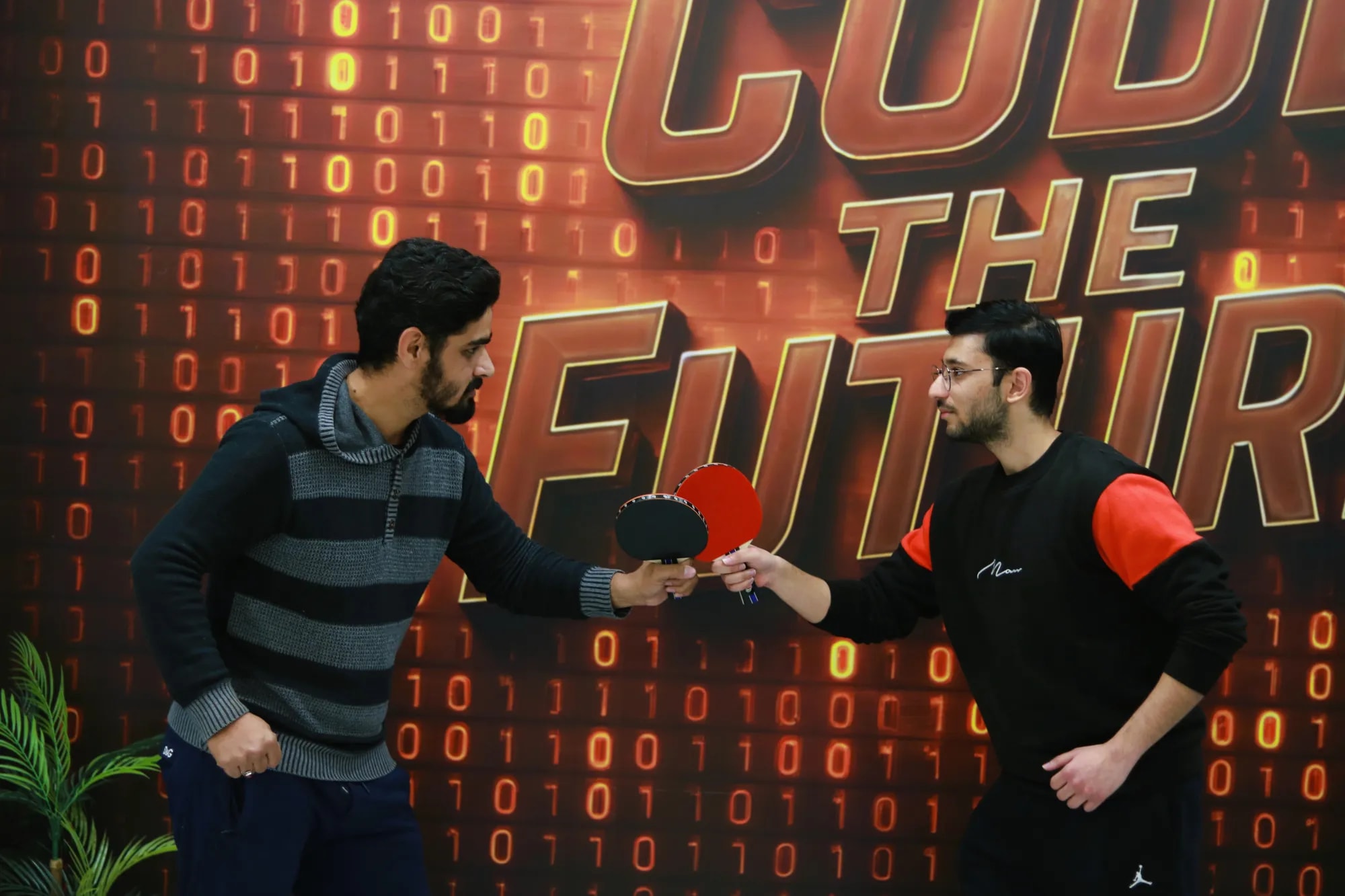 Two colleagues shaking hands across a table-tennis table before a match